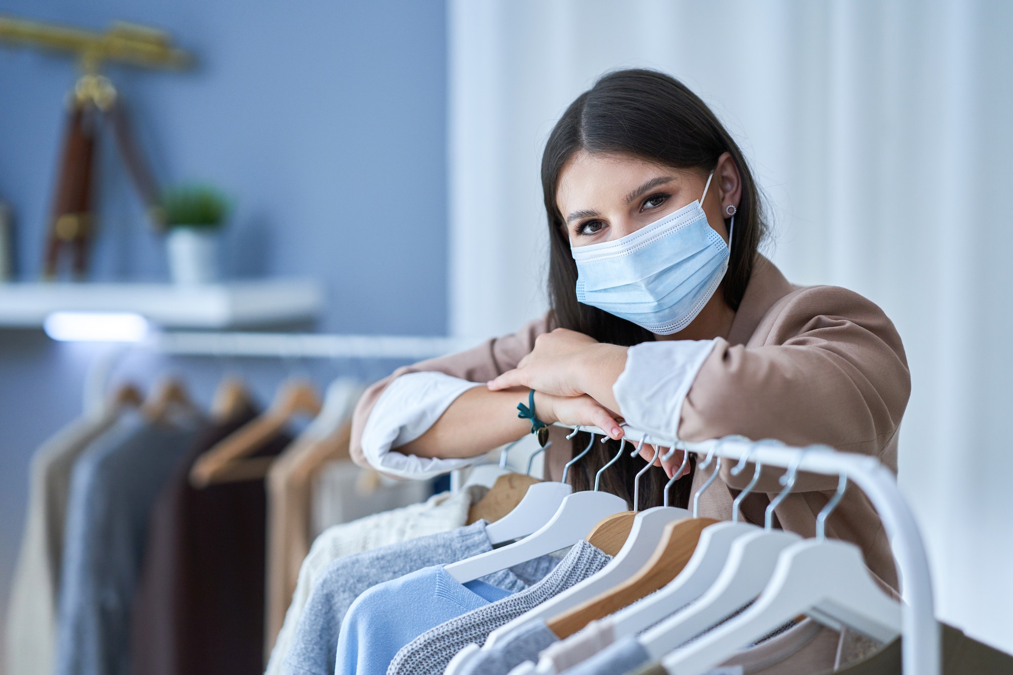 Young woman as a store manager with clothes in mask